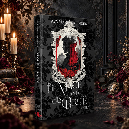 Stolen Magic (The Mage and His Brute Book 2) Special Edition Hardback by Ava Marie Salinger among candles, red roses and a cameo pendant