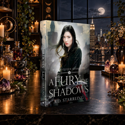 A Fury of Shadows (Witch Queen Book 5) Hardback by A.D. Starrling on a marble table by a moonlit window over the New York skyline